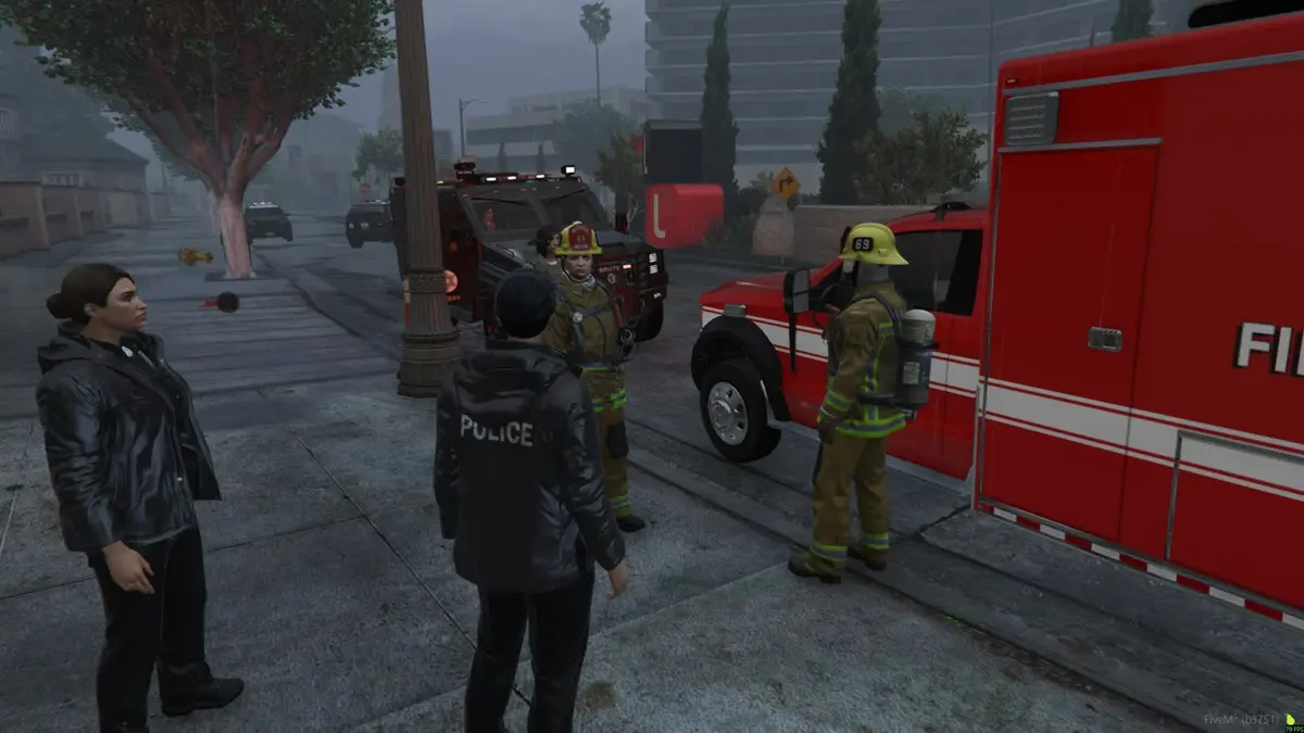 Police and firefighters working a scene in the rain beside a fire engine
