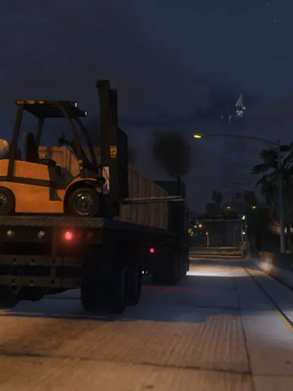 A forklift loaded onto a flatbed truck at night