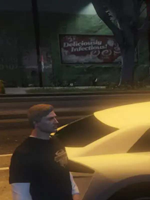A man waiting beside a parked car on a dark street